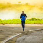man in track suit jogging on concrete road