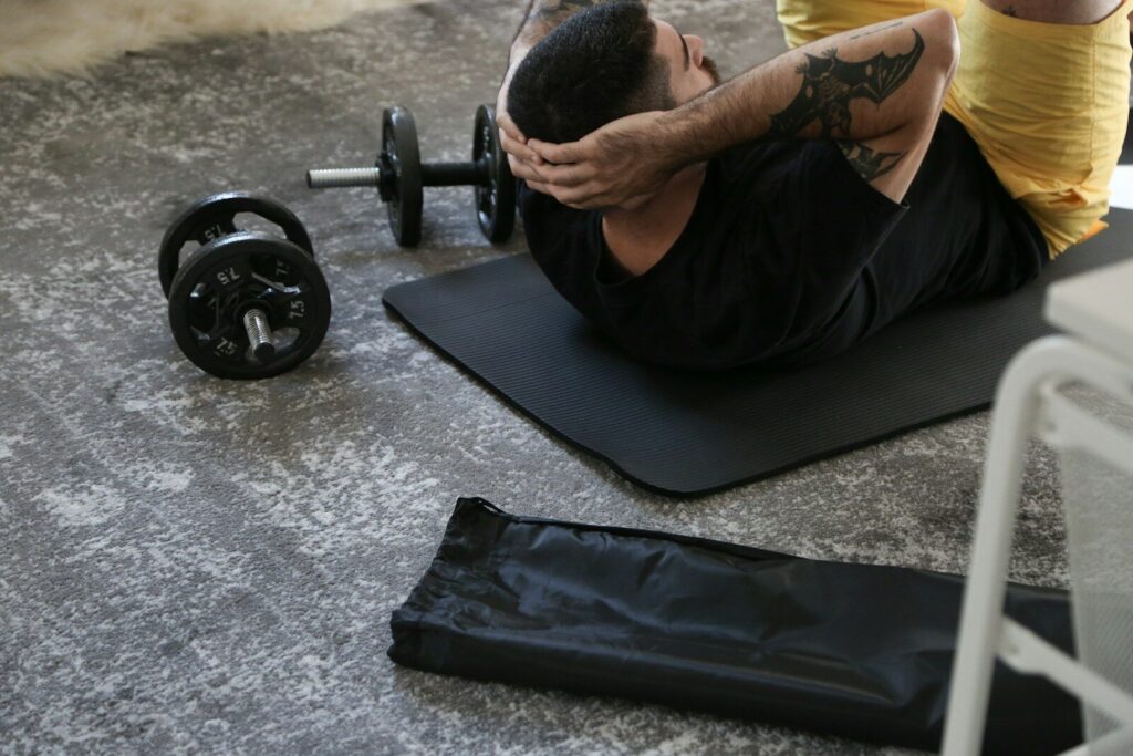 About a man is doing exercises on a mat with a barbell