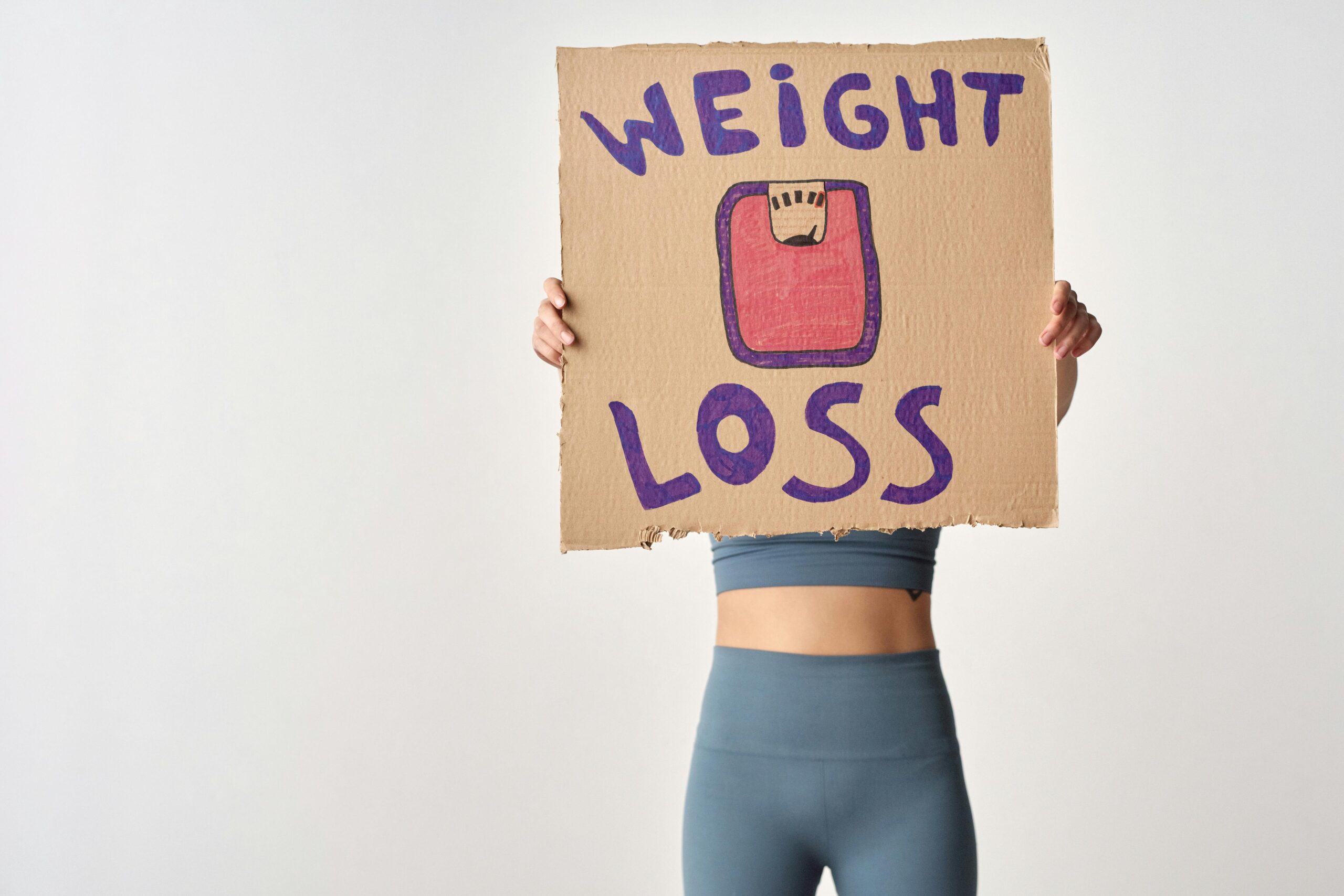 Blog page Person holding 'weight loss' sign for fitness motivation and health goals.